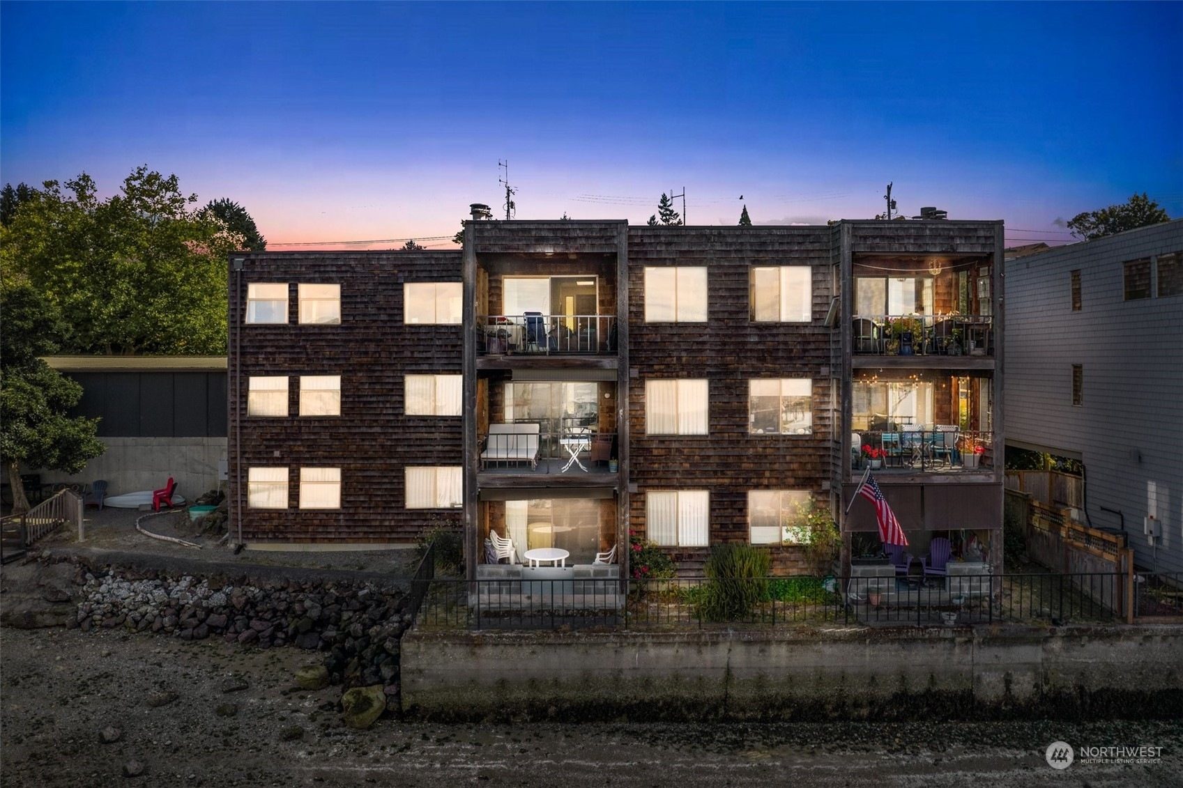 Waterfront apartment building at dusk with lit balconies